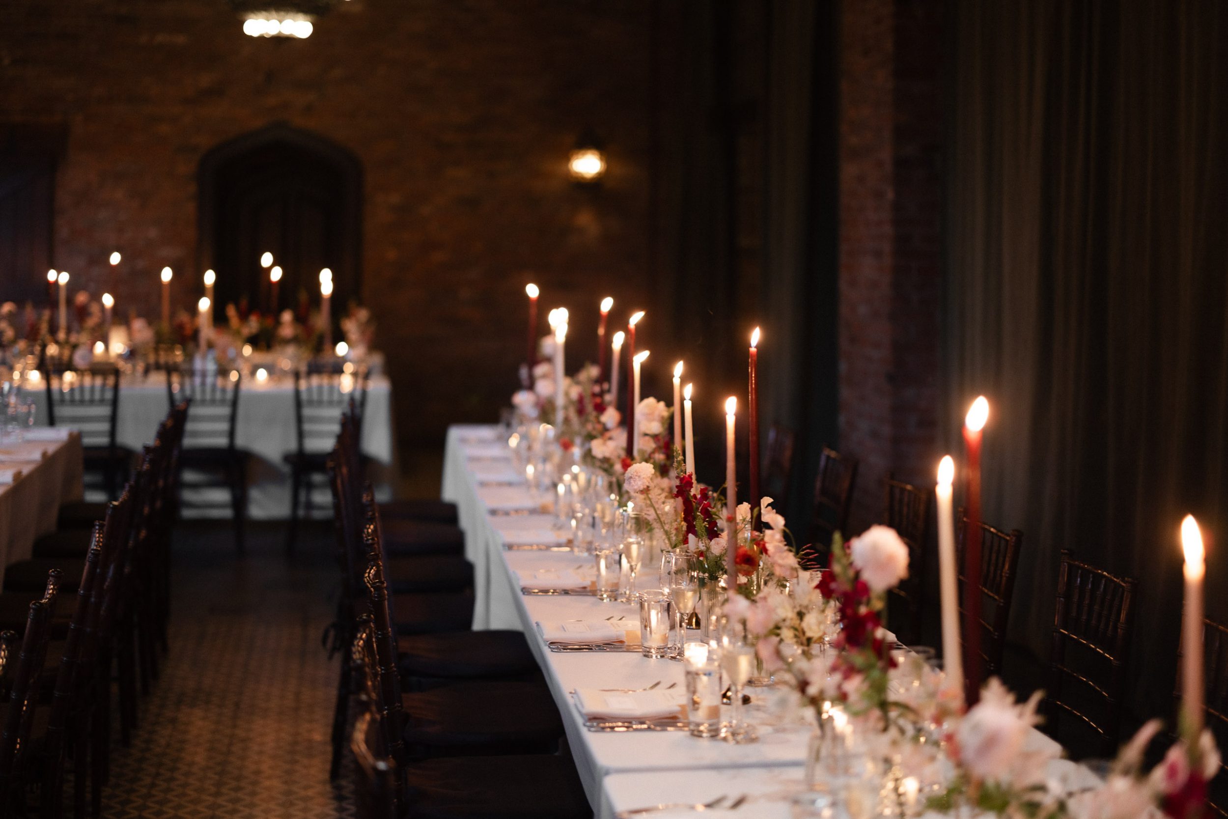 A stylish New York City wedding, rustic brick walls, velvet drapery, and golden candlelight, capturing the intimate, cinematic atmosphere of the iconic venue.
